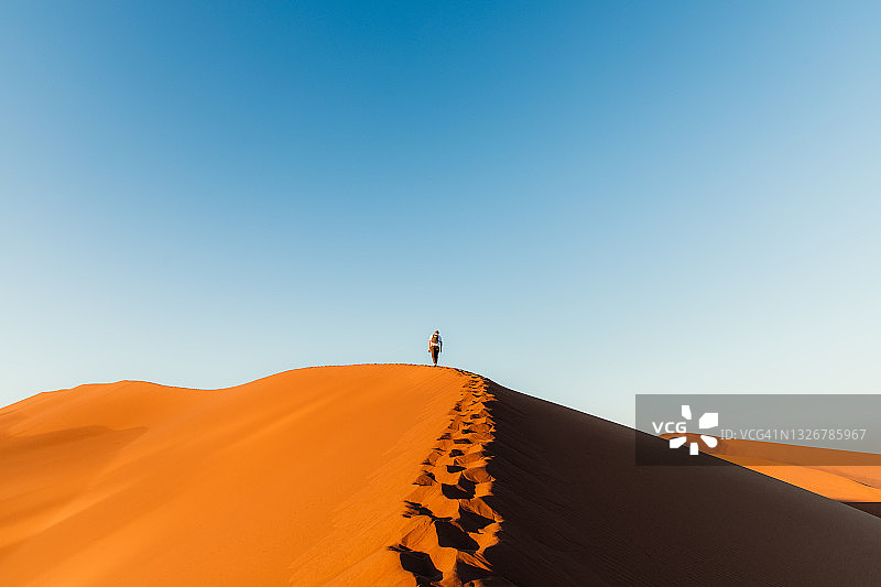 在纳米比亚死亡谷沙丘顶端欣赏日出的旅行者图片素材