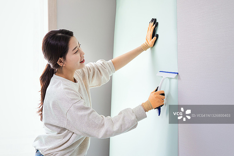 女人在墙上贴壁纸图片素材