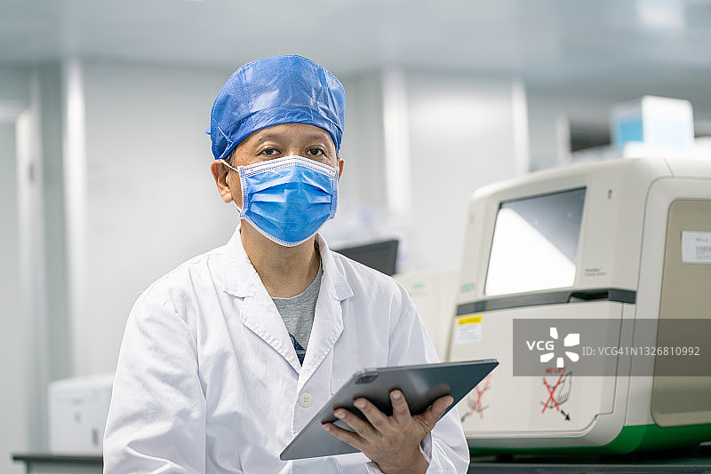 亚洲男医生拿着平板电脑看着镜头图片素材