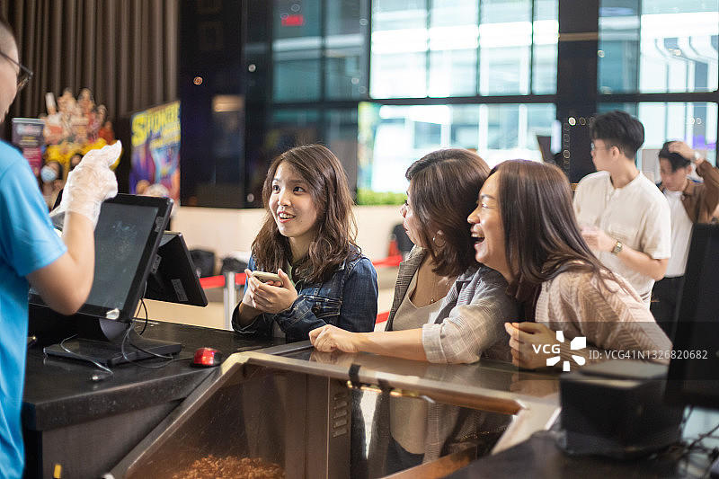 一群亚洲中国女人在特许摊位购买爆米花和饮料图片素材