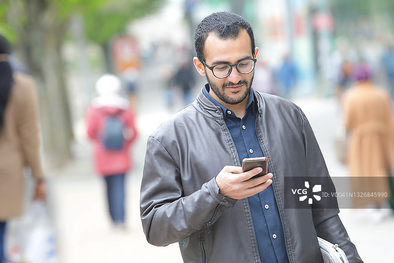 男人在城市长廊行走时发短信图片素材
