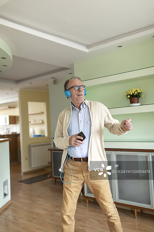 戴着耳机在家中开心的老人图片素材