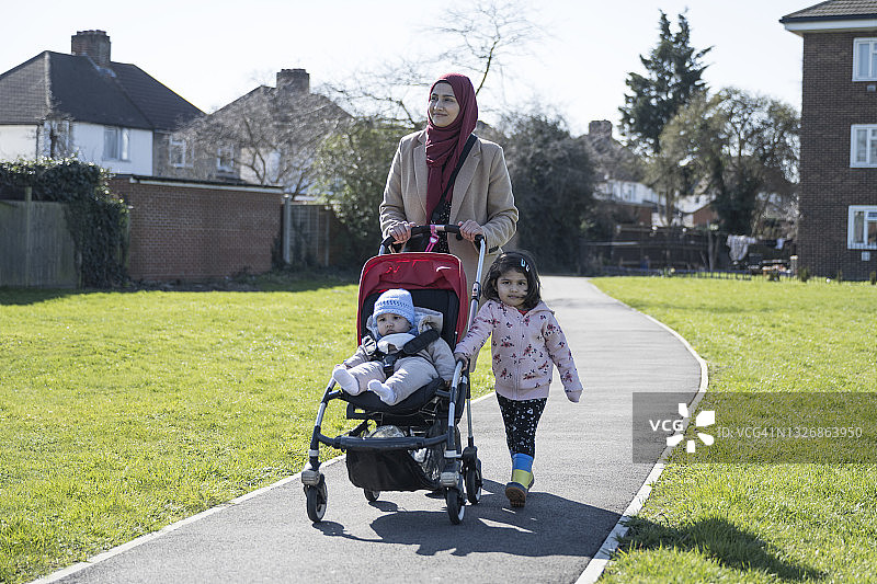在阳光下散步的英国亚裔母女和婴儿图片素材