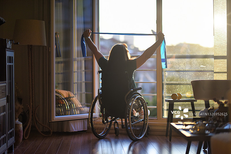 坐在轮椅上用阻力带锻炼的女人图片素材