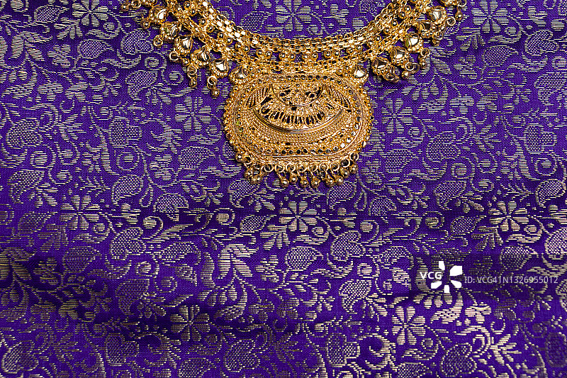 紫色纱丽背景上的印度黄金首饰图片素材