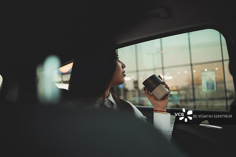 坐在汽车后座、前往商务会议的年轻黑发职业女性图片素材