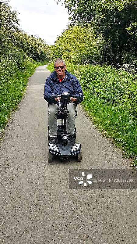 中年男人在夏日 countryside 的赛道上驾驶他的电动代步车图片素材