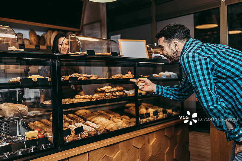 小型企业：面包店女助理快乐地递给顾客糕点图片素材