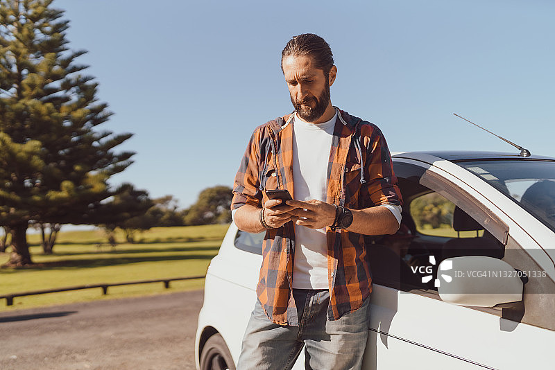 在户外使用手机的男人和汽车图片素材