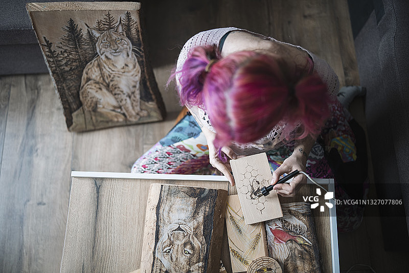 女艺术家在木板上用烙画笔创作动物肖像顶视图图片素材