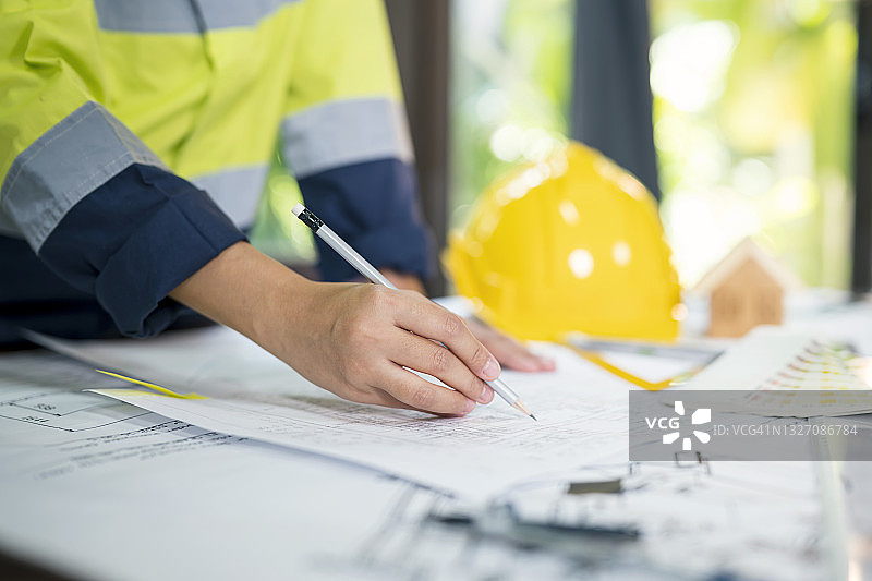 建筑师在办公室桌上审查建筑工程蓝图特写图片素材