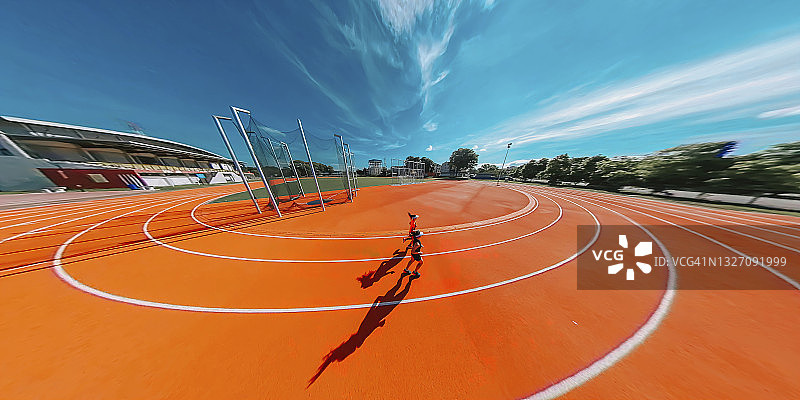 早上在田径运动场上，两条亚裔中国女性运动员在女子跑道上跑步的鱼眼侧视高角度照片图片素材