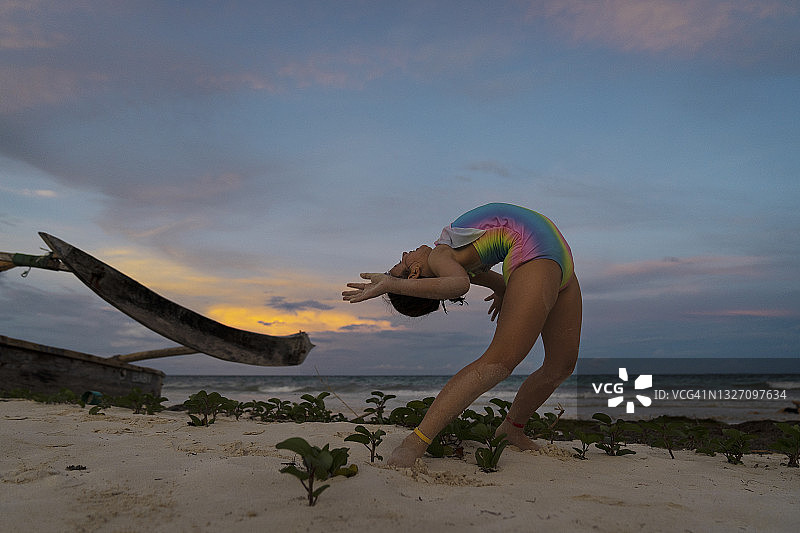 年轻瑜伽女孩在印度洋附近练习瑜伽，做桥式运动或后弯。肯尼亚，非洲图片素材