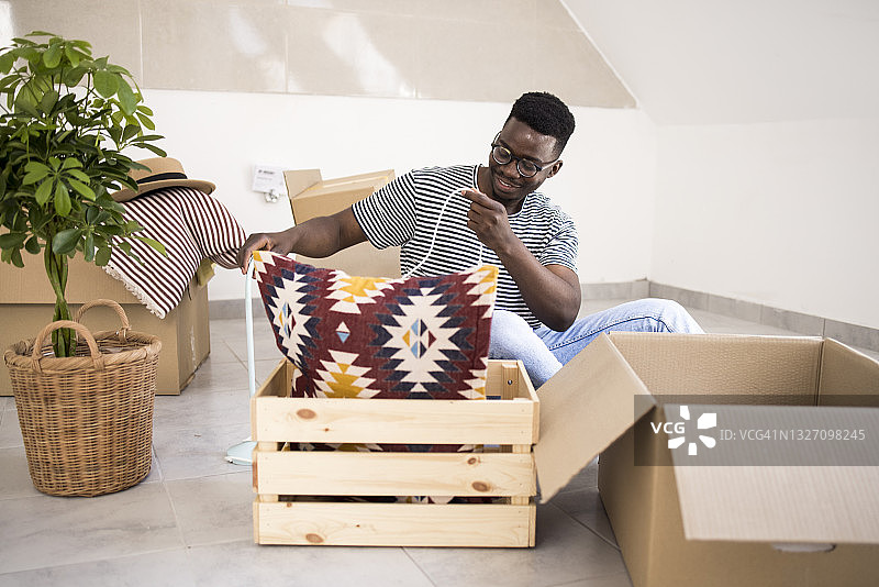 快乐的年轻非裔美国人在新家中打开他的物品图片素材