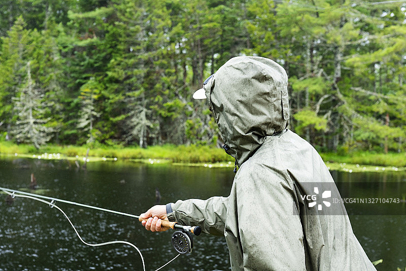 一位飞蝇钓手在雨中湖上钓鱼图片素材