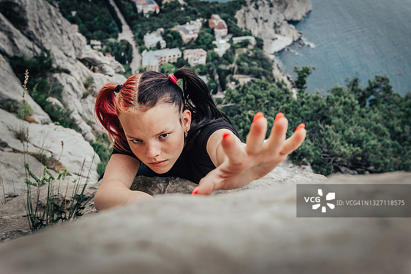 勇敢的粉色双马尾小女孩攀爬岩壁特写图片素材