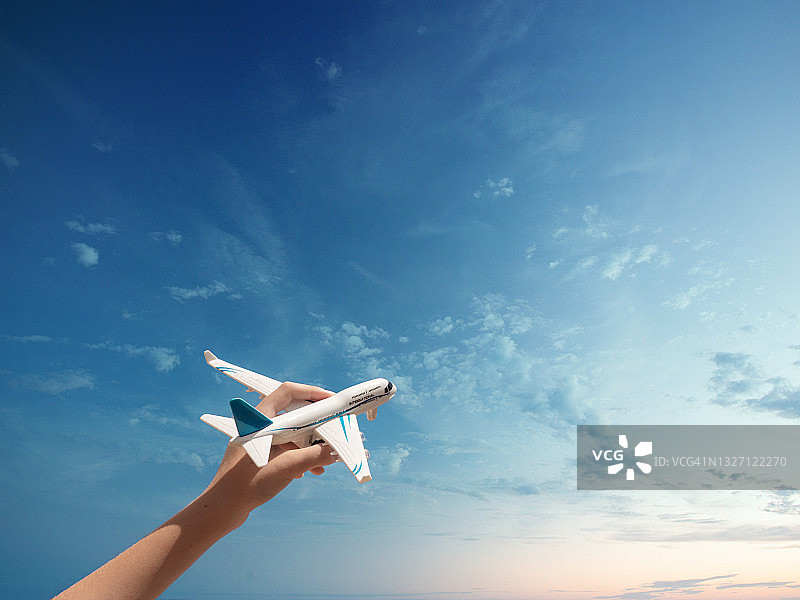 男孩的手拿着模型飞机，蓝天白云下的飞机图片素材