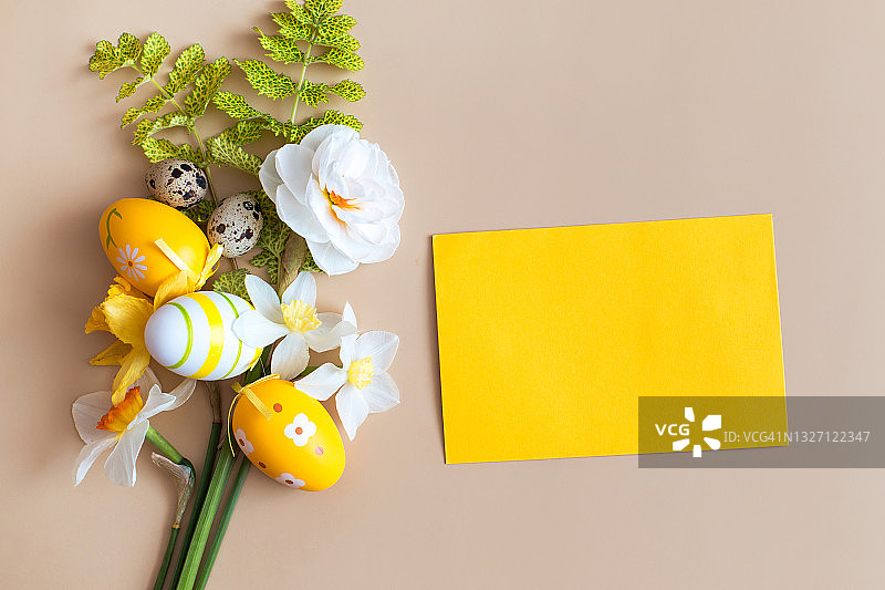 复活节构图：米色背景上的复活节彩蛋、鲜花和黄色纸张图片素材