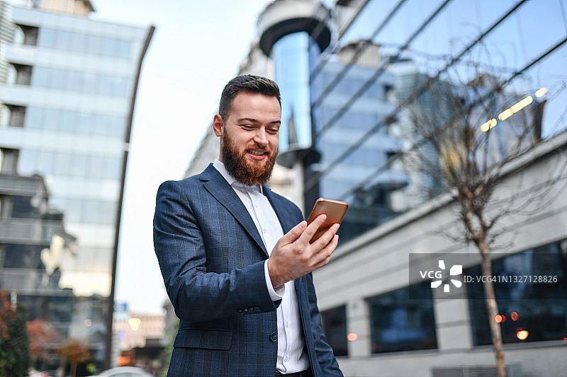 留着胡子的优雅男人在约会软件上查找位置时微笑图片素材