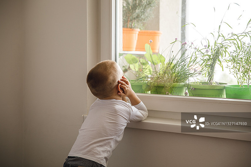 透过窗户，渴望在外面玩耍的小男孩图片素材