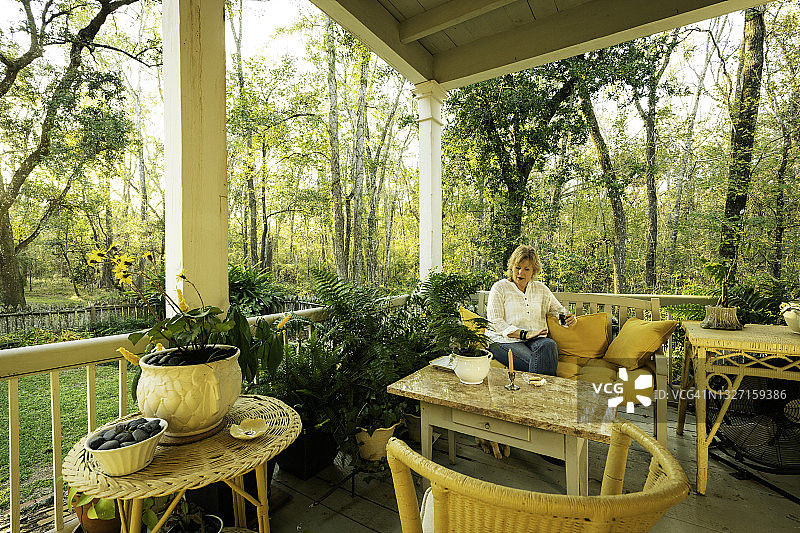 在路易斯安那州拉斐特马丁湖沼泽边缘的克里奥小屋放松的女性游客图片素材