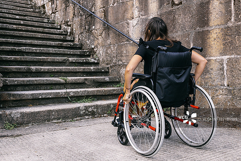 坐在轮椅上的年轻女子看着楼梯的背影图片素材