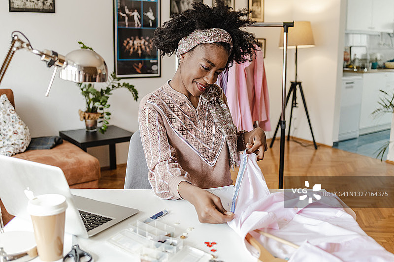 年轻女裁缝在她的家庭工作室工作图片素材