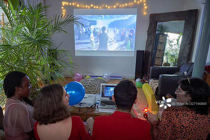 四个人坐在沙发上看投影仪上的虚拟直播活动图片素材