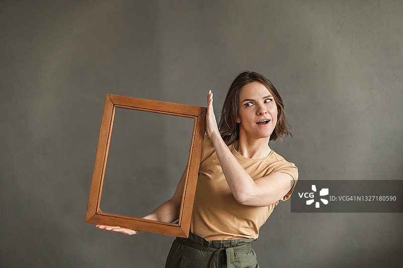 手持相框的快乐女士，灰色背景图片素材