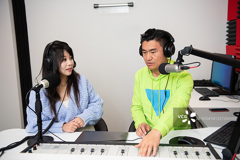 在广播电台工作的亚洲男女主持人图片素材