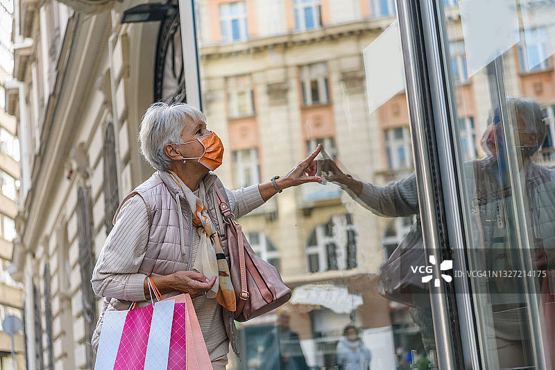 疫情期间，一位年长的妇女在城市里散步和购物图片素材