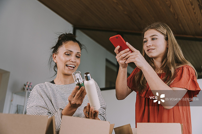 在家中拍摄中年妇女手持美容产品的少女图片素材