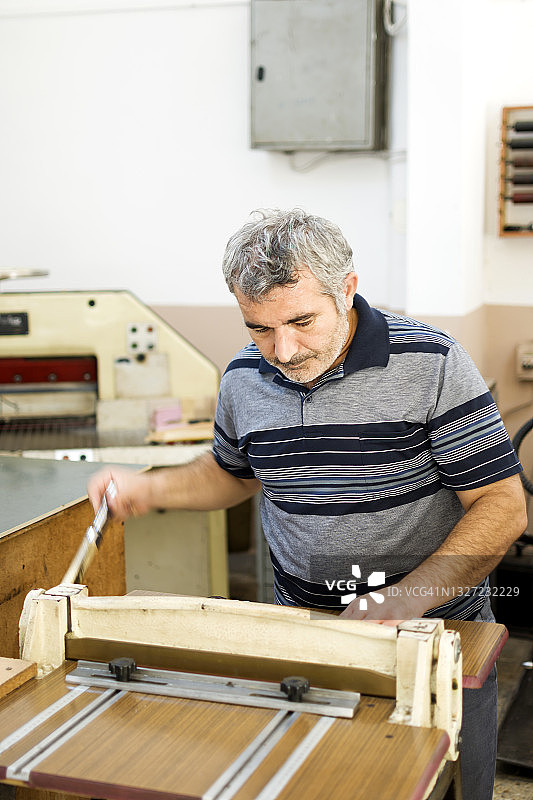 在印刷厂使用切割机的男人图片素材