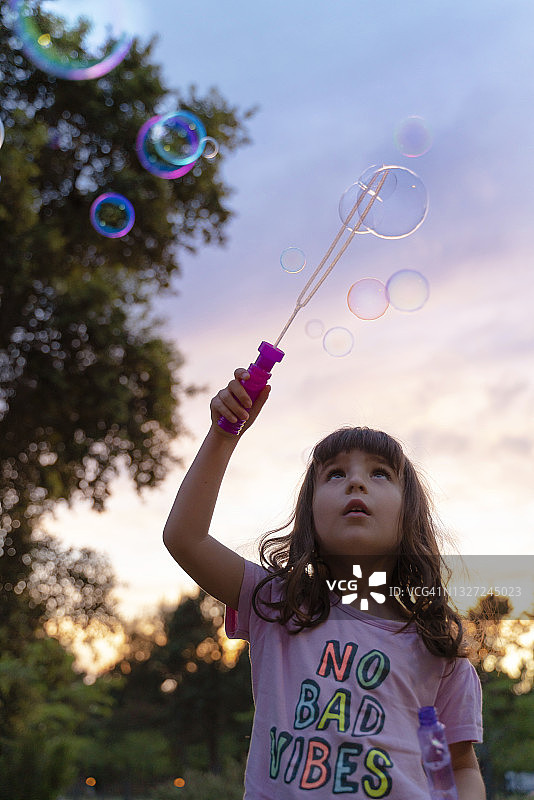 在日落时分玩耍吹泡泡的女孩图片素材