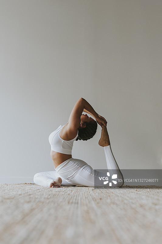 在工作室靠墙练习瑜伽的柔韧瑜伽士图片素材