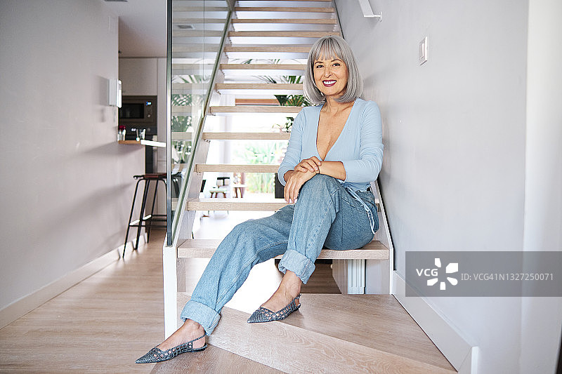 在家中坐在楼梯上的微笑中年妇女图片素材