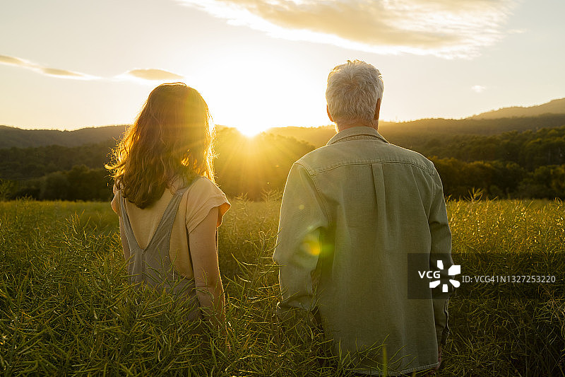 父女在日落时分站在田野里图片素材