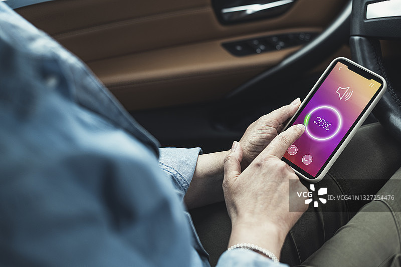 女人坐在车里通过智能手机调整音量图片素材