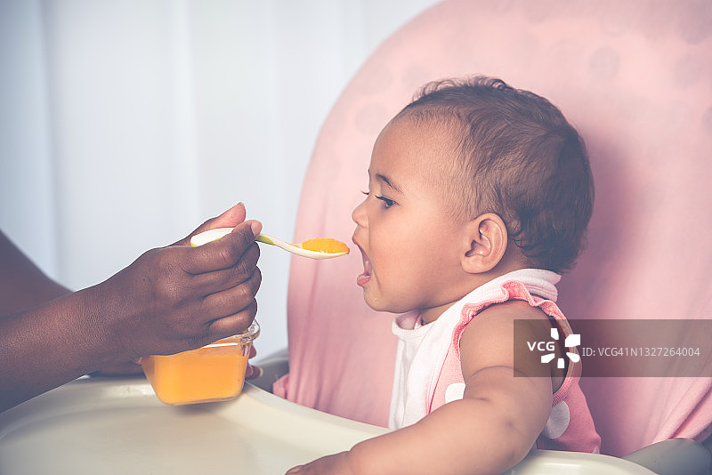 可爱婴儿用小勺吃芒果泥图片素材