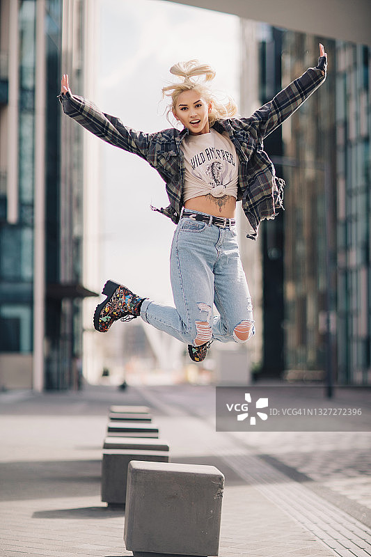 快乐的金发女人跳过空旷的城市街道图片素材