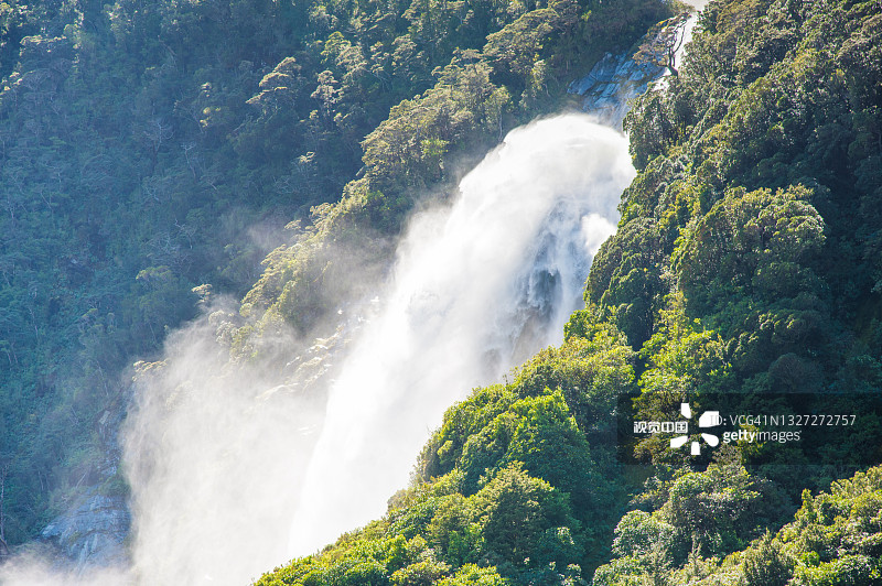 自然景观背景瀑布落在雾蒙蒙的绿色山在新西兰米尔福德峡湾图片素材