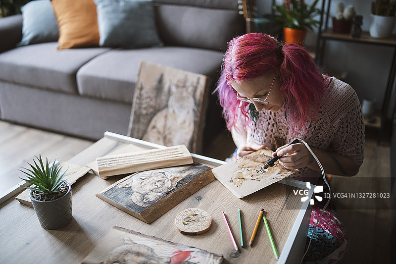 年轻女艺术家在木板上进行烙画创作图片素材