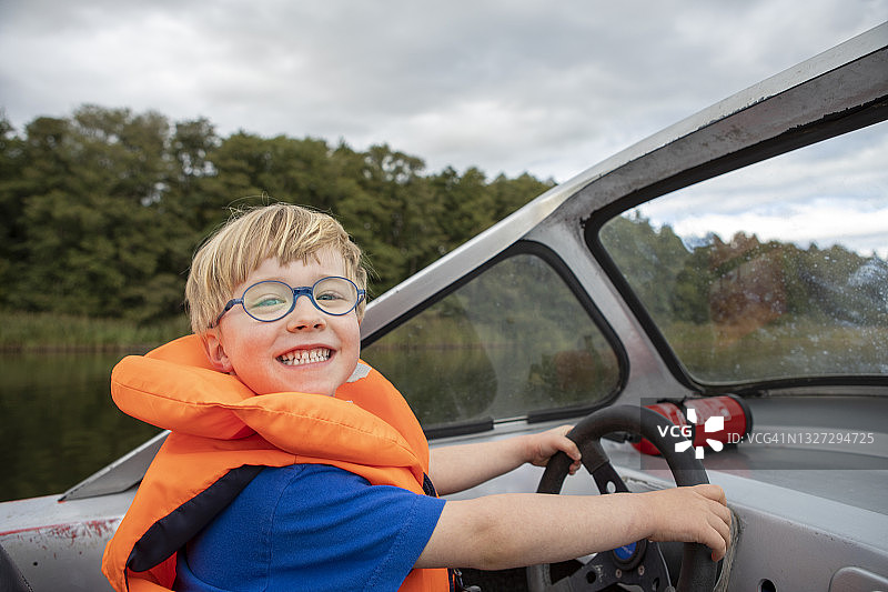 男孩驾驶摩托艇对着镜头微笑图片素材