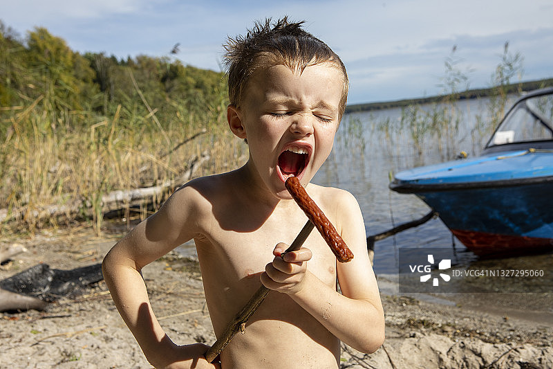 拿着香肠的小男孩假装唱歌图片素材