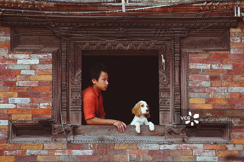 眺望巴克塔普尔杜巴广场的年轻尼泊尔男子和狗图片素材