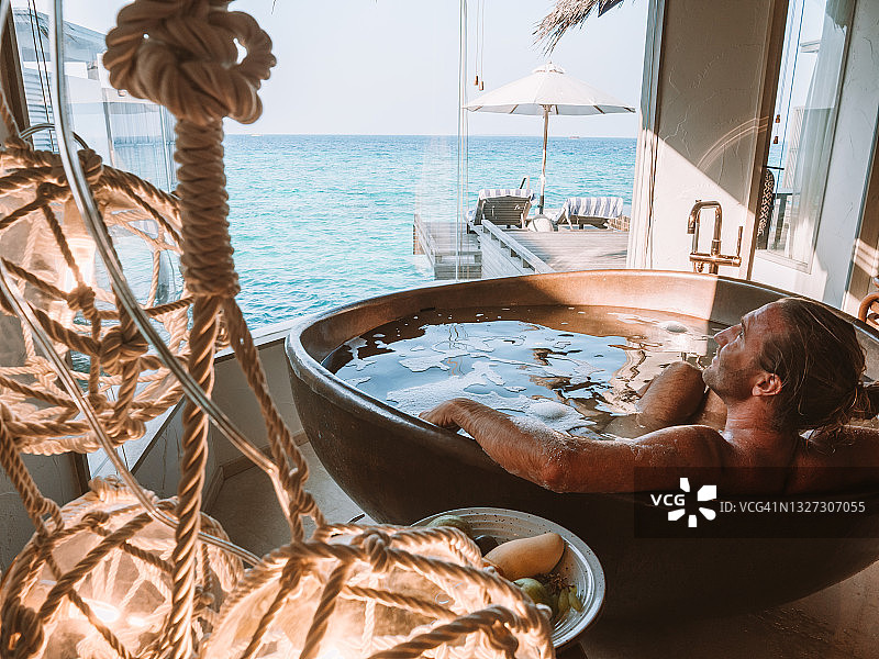 男子在豪华海景别墅中泡澡的背影图片素材