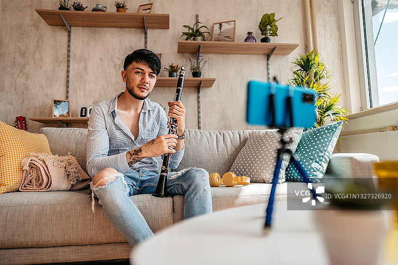 男人在手机上制作单簧管演奏教程图片素材