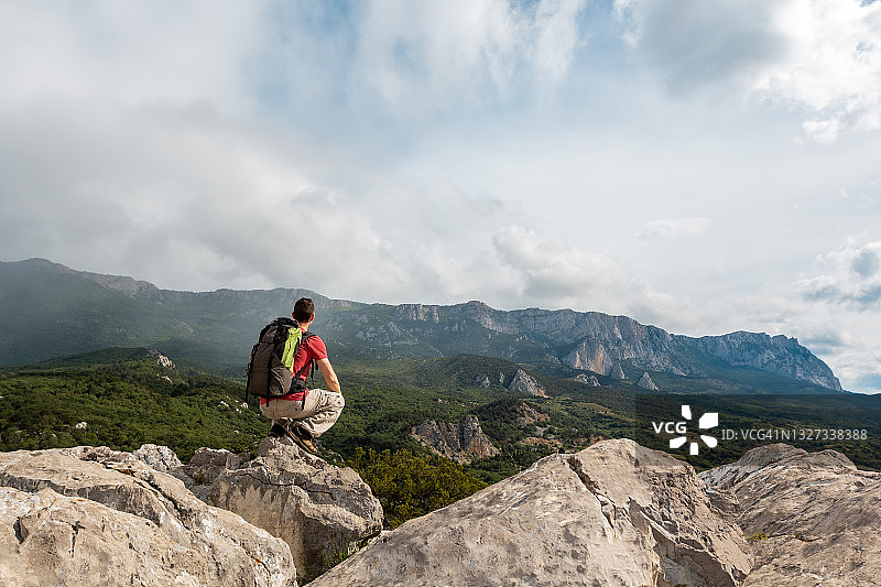 坐在山上休息的背着背包的年轻男人图片素材