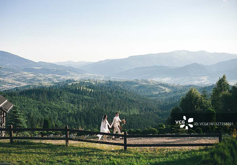 幸福的夫妇在夏天在户外庆祝婚礼。山脉、绿色森林和丘陵的美丽景色。图片素材
