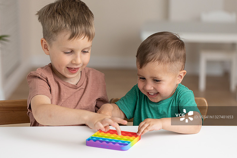 玩Pop It指尖玩具的可爱儿童：新型抗压游戏——按压式泡泡解压玩具，用于儿童释放和发展的感觉玩具图片素材